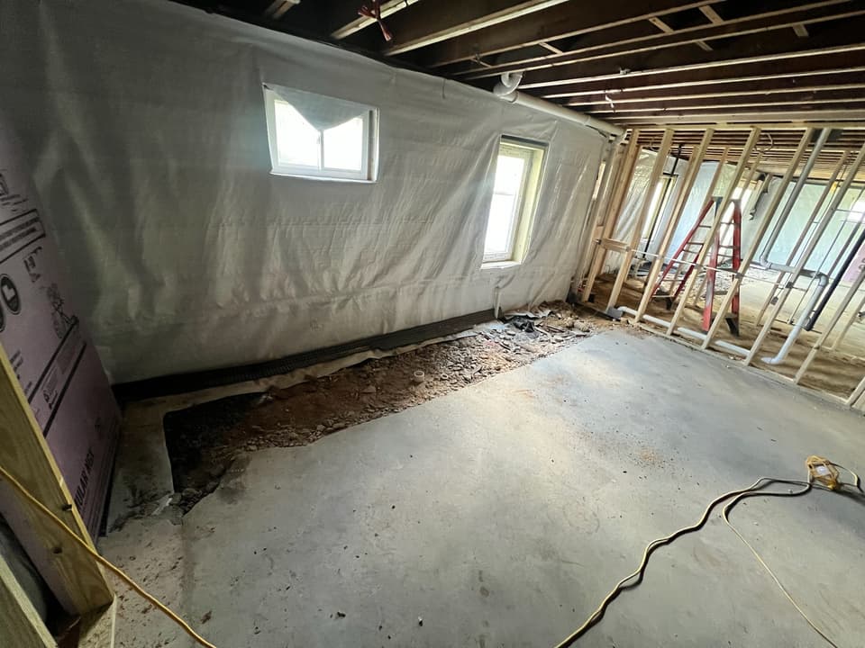 Trench opened along the base of a lined basement wall during interior drainage work