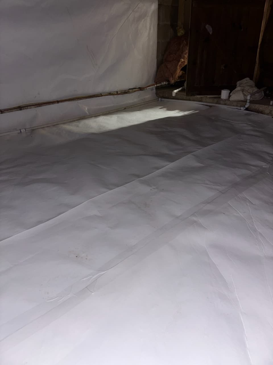 White floor liner laid across a crawl space floor