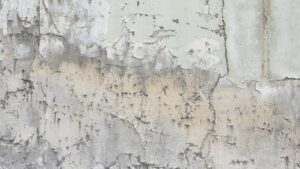 Weathered wall with chipped, peeling paint in beige, gray, and white tones revealing multiple layers and textures.